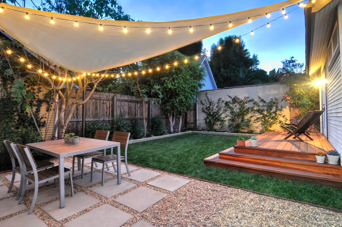Evening backyard with shade sail, string lights, lawn and redwood deck